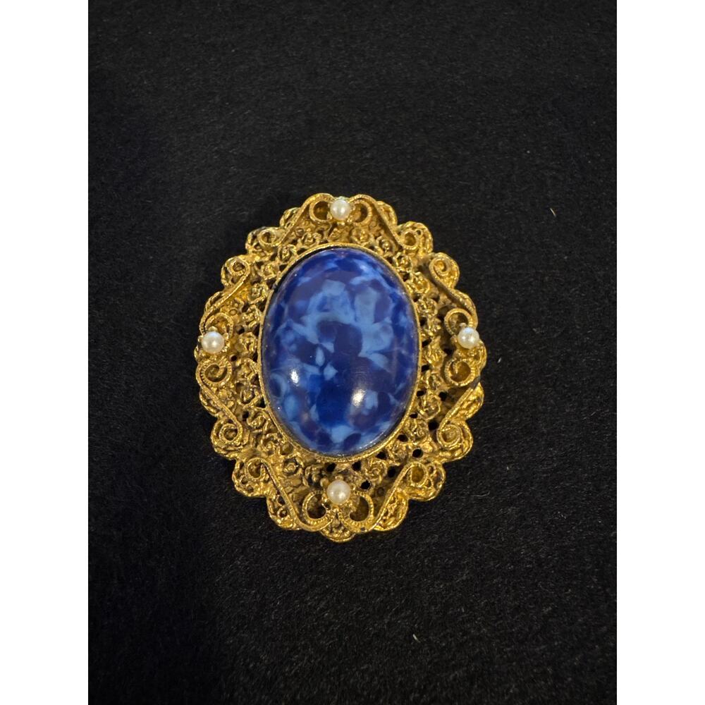 Vintage Art Nouveau blue cabochon set in a gold-tone filigree metal frame.
